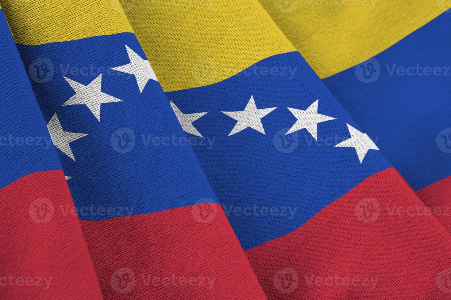 Venezuela flag with big folds waving close up under the studio light indoors. The official symbols and colors in banner photo