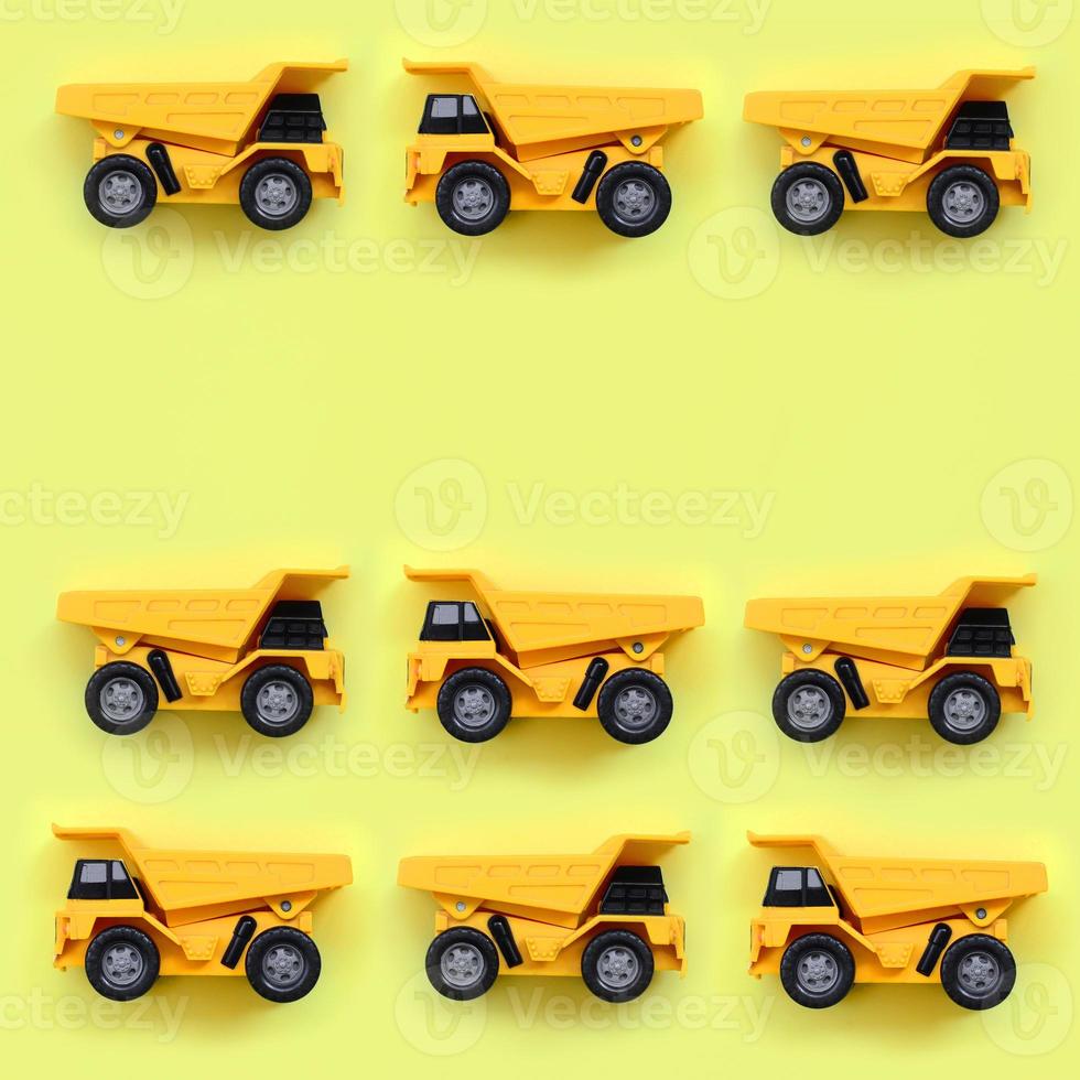 Many small yellow toy trucks on texture background of fashion pastel yellow color paper in minimal concept photo