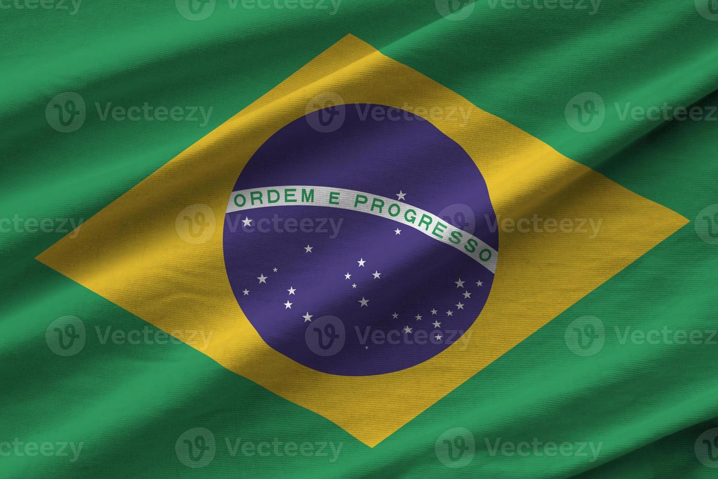 Brazil flag with big folds waving close up under the studio light indoors. The official symbols and colors in banner photo