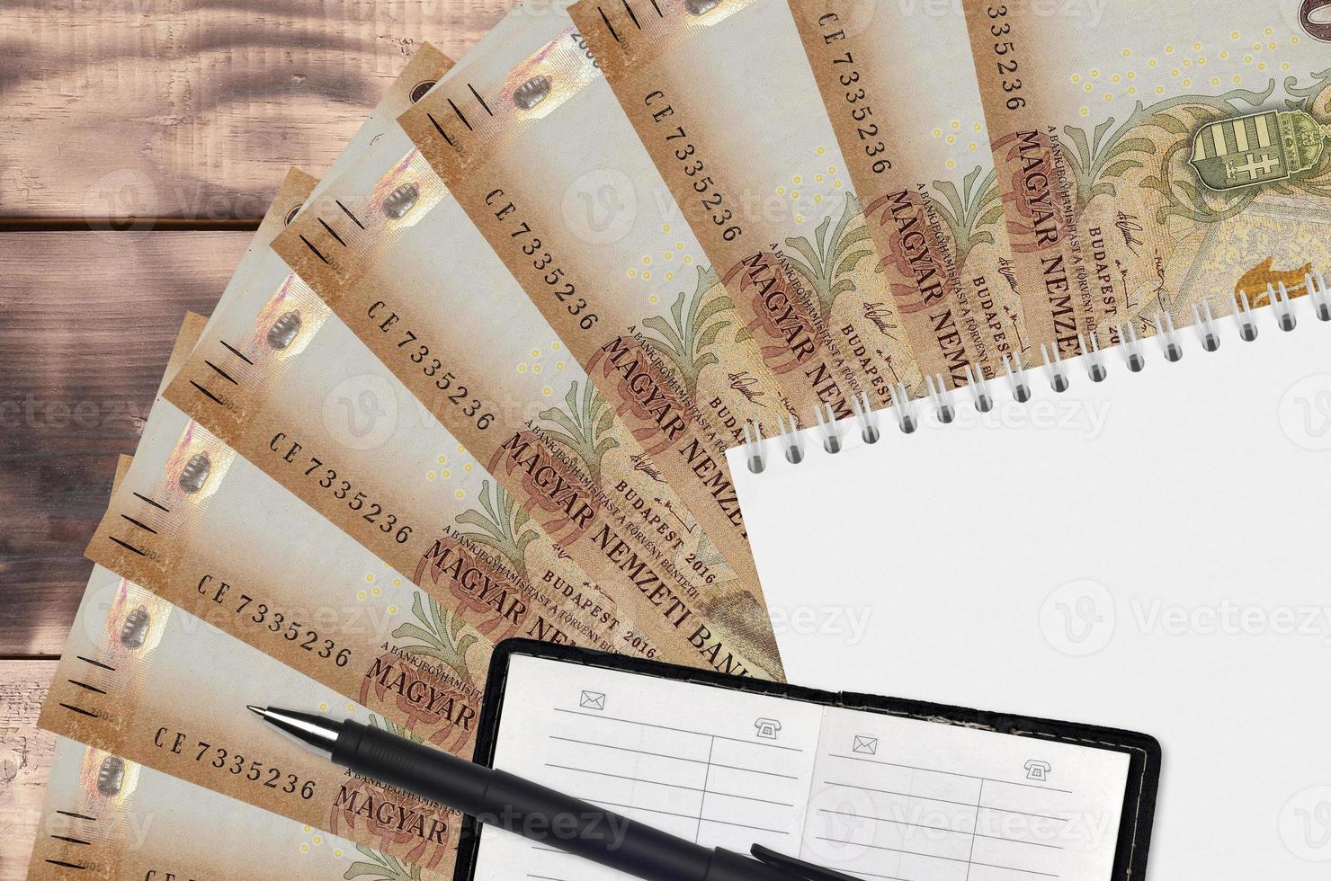 2000 Hungarian forint bills fan and notepad with contact book and black pen. Concept of financial planning and business strategy photo