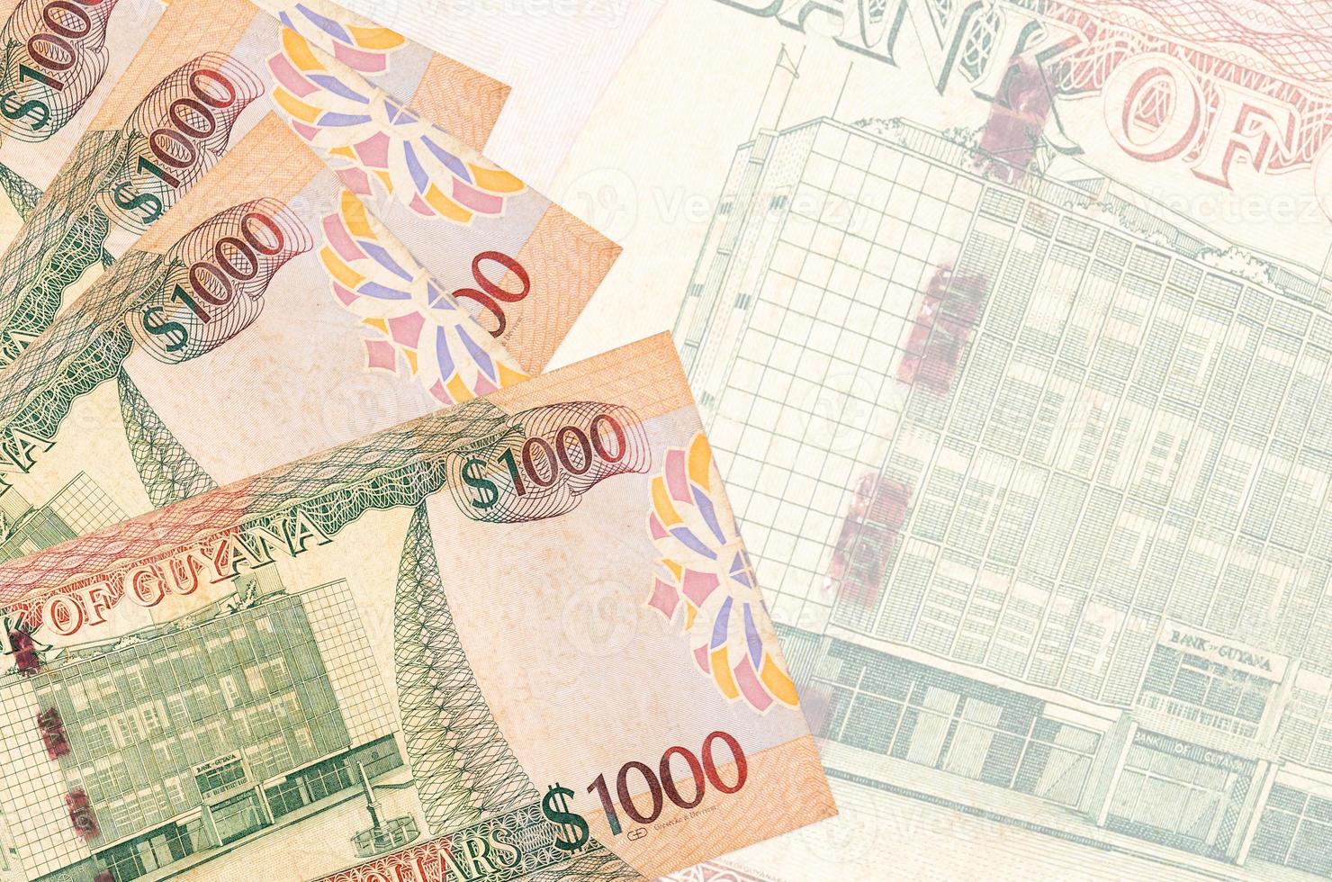 1000 Guyanese dollars bills lies in stack on background of big semi-transparent banknote. Abstract business background photo