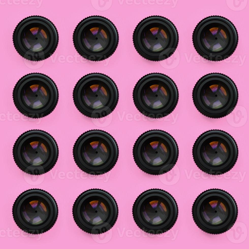 A few camera lenses with a closed aperture lie on texture background of fashion pastel pink color paper in minimal concept. Abstract trendy pattern photo