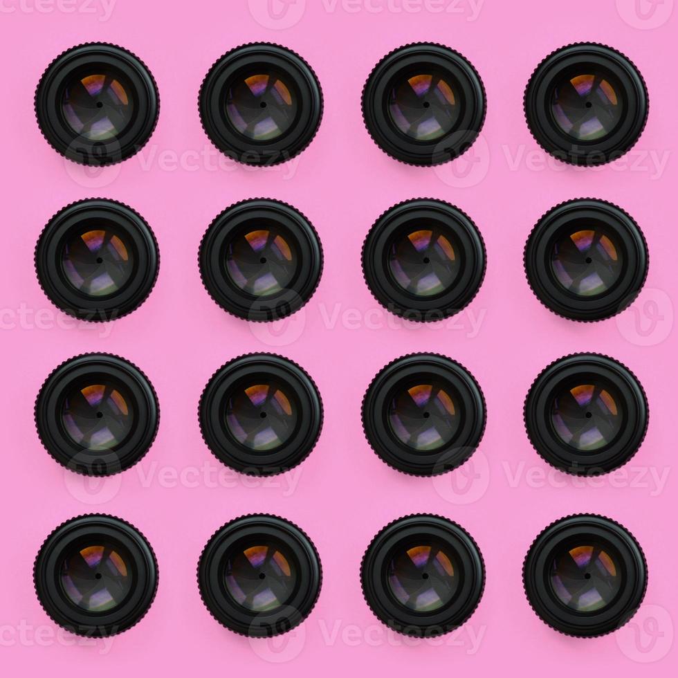 A few camera lenses with a closed aperture lie on texture background of fashion pastel pink color paper in minimal concept. Abstract trendy pattern photo