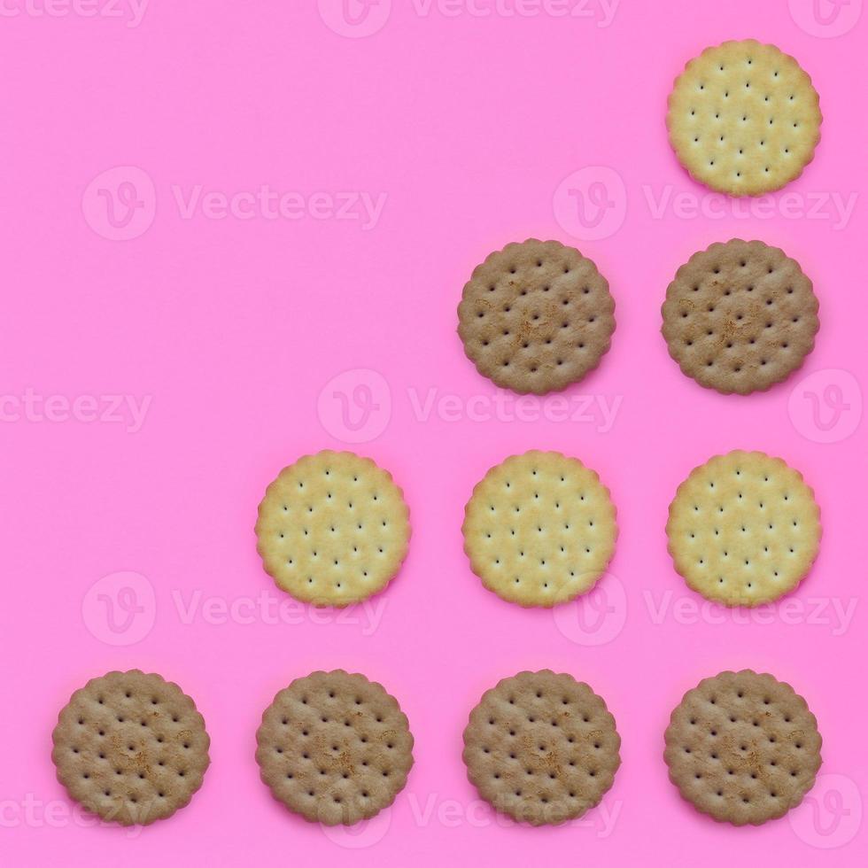 Pattern of a brown biscuits on a pink background. Trendy minimal concept of food and dessert. Abstract flat lay, top view photo