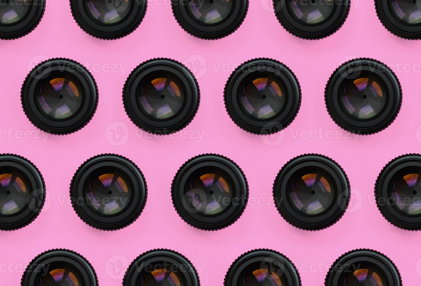 A few camera lenses with a closed aperture lie on texture background of fashion pastel pink color paper in minimal concept. Abstract trendy pattern photo