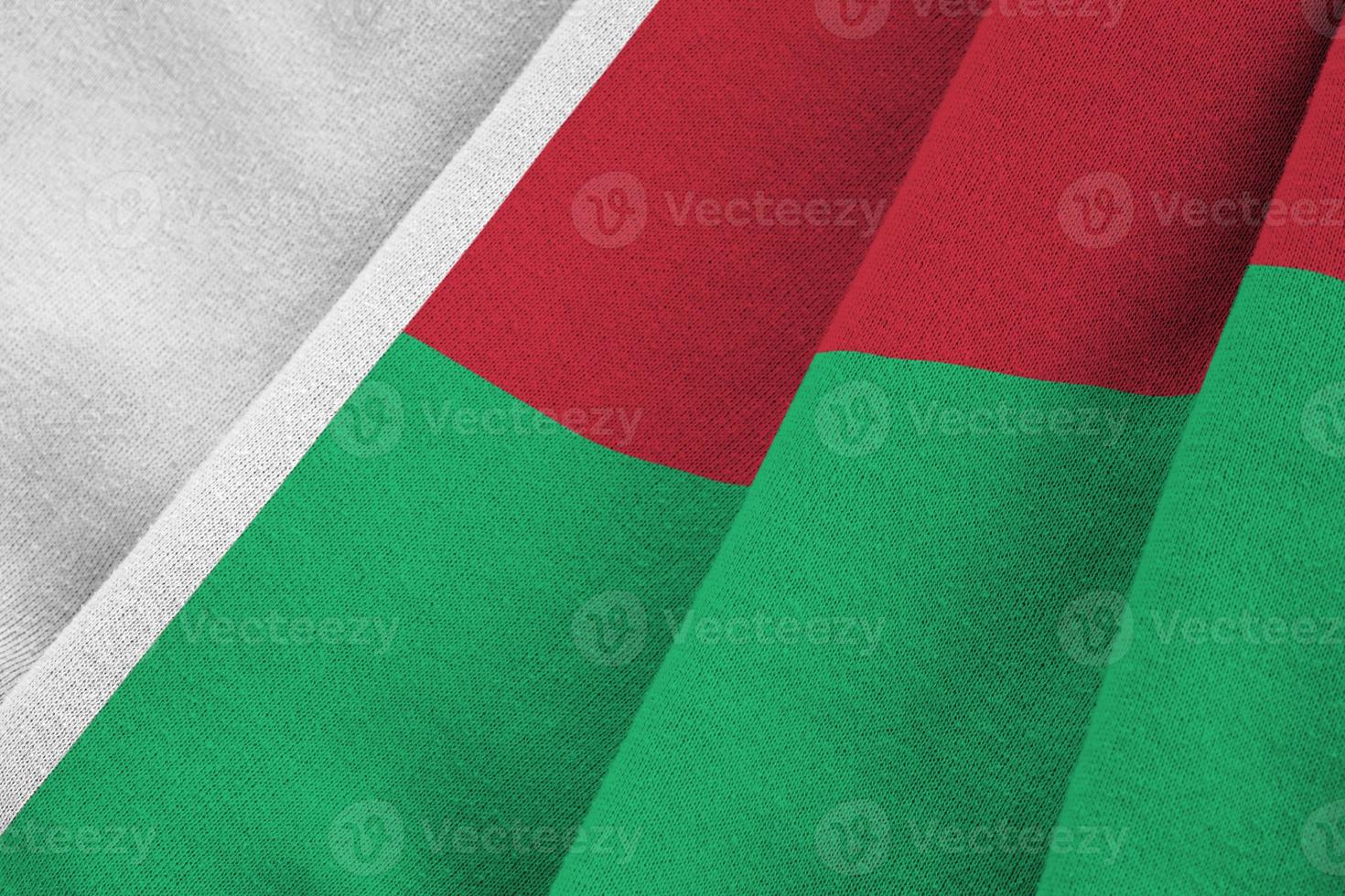 Madagascar flag with big folds waving close up under the studio light indoors. The official symbols and colors in banner photo