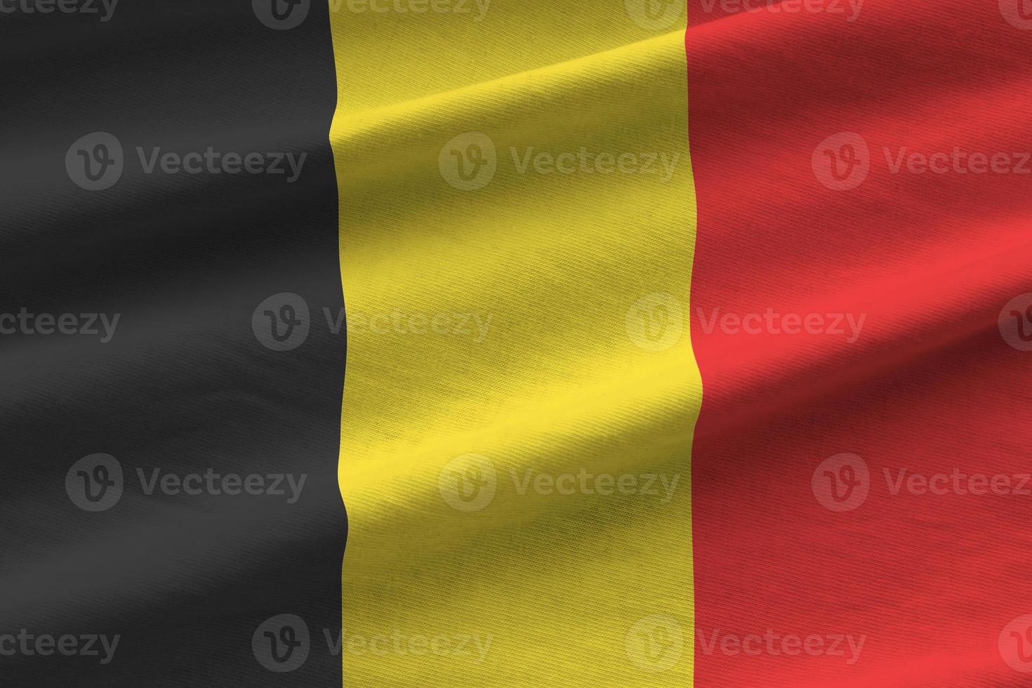 Belgium flag with big folds waving close up under the studio light indoors. The official symbols and colors in banner photo