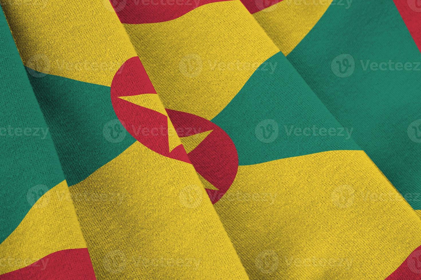 Grenada flag with big folds waving close up under the studio light indoors. The official symbols and colors in banner photo