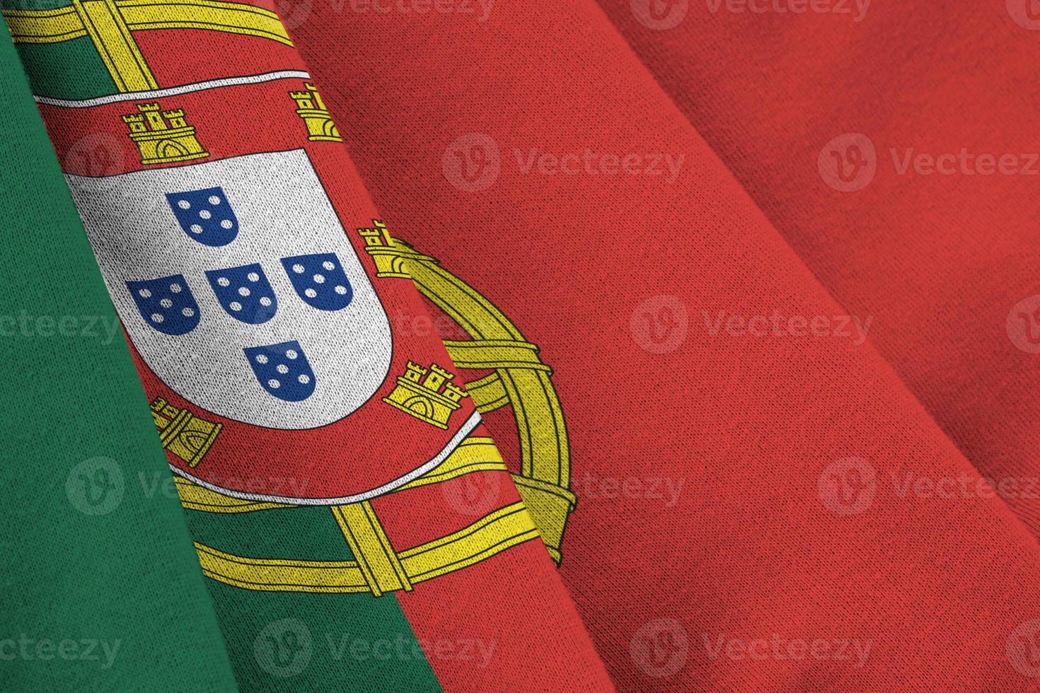 Portugal flag with big folds waving close up under the studio light indoors. The official symbols and colors in banner photo