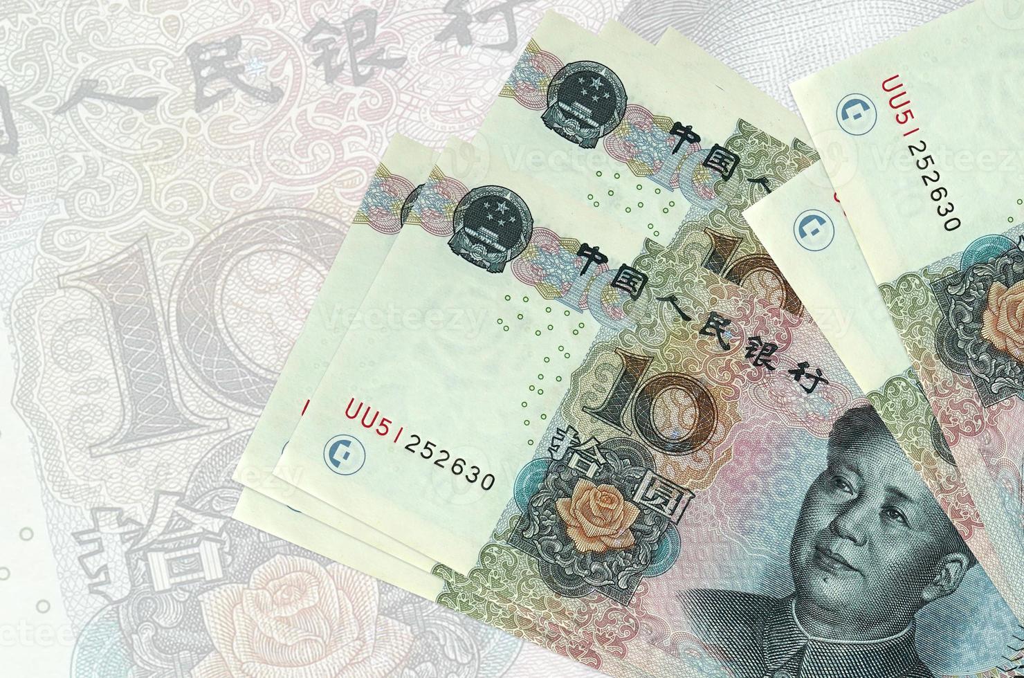 10 Chinese yuan bills lies in stack on background of big semi-transparent banknote. Abstract presentation of national currency photo