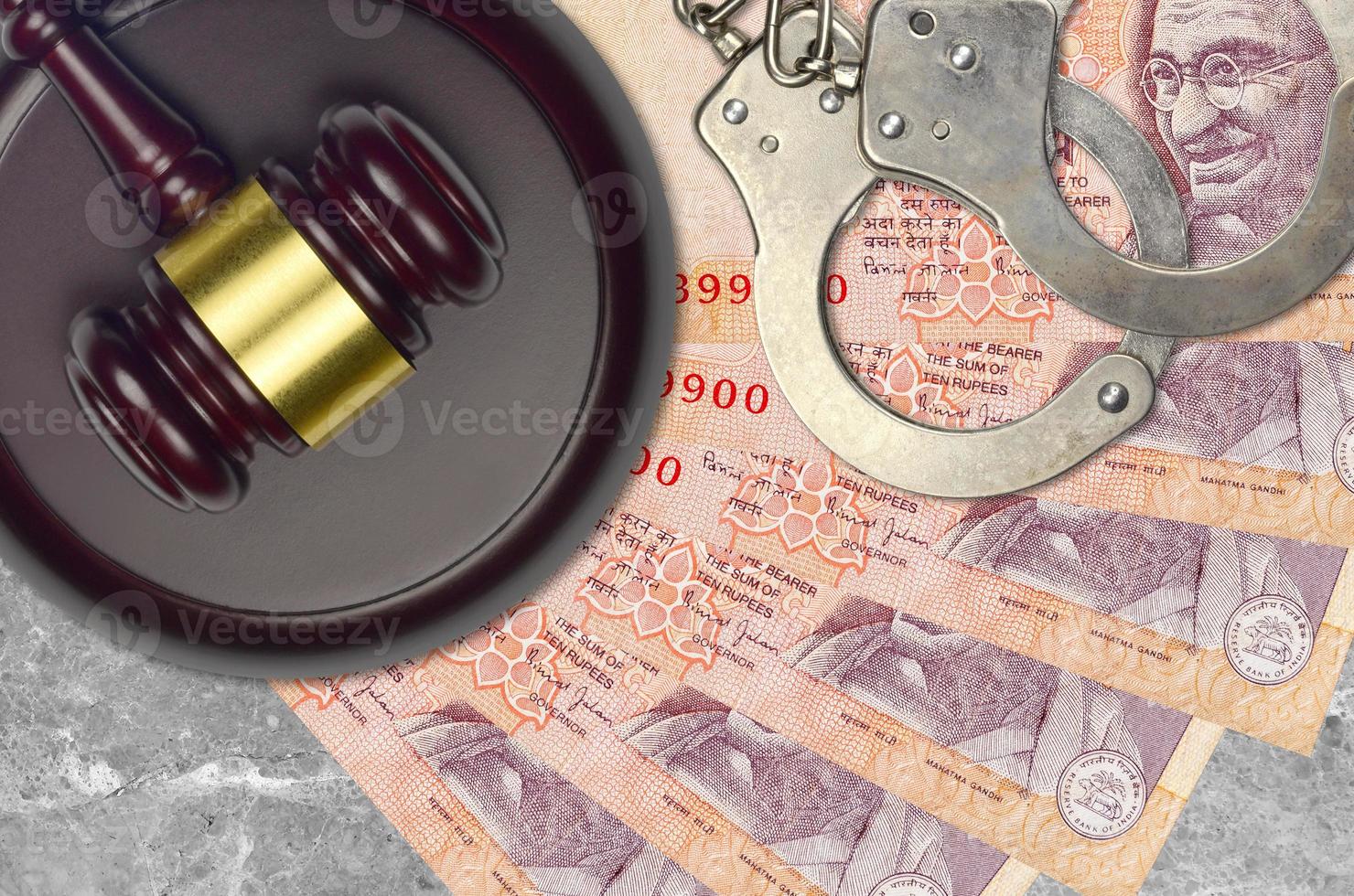 10 Indian rupees bills and judge hammer with police handcuffs on court desk. Concept of judicial trial or bribery. Tax avoidance photo