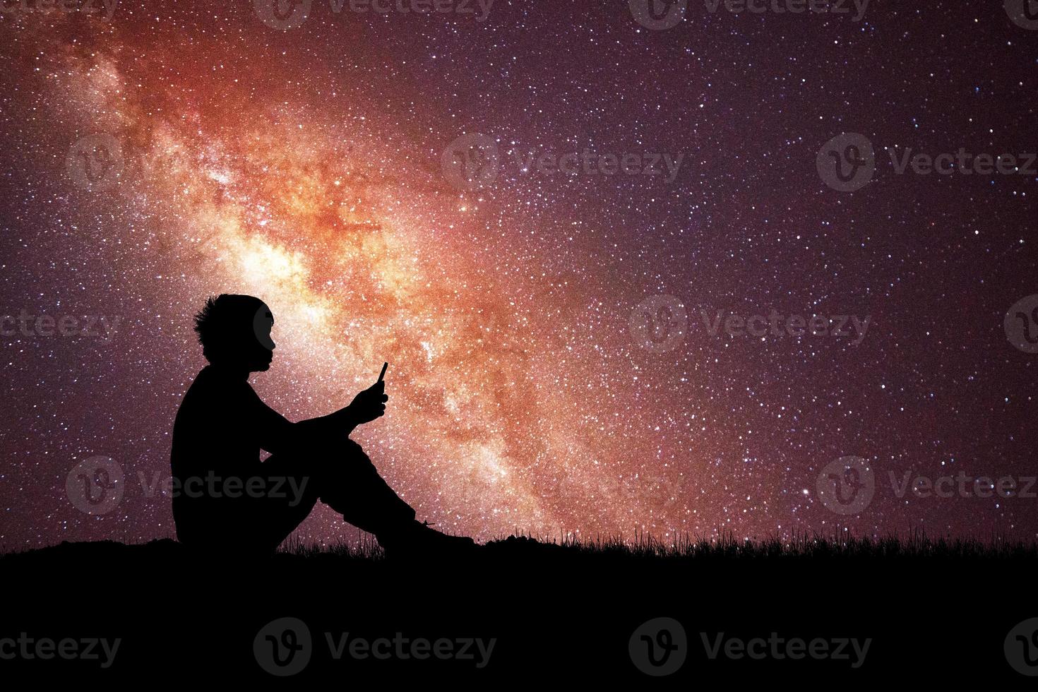 Loneliness, despair and regret concept. Lonely man in the meadow against the backdrop of stars and the Milky Way. photo