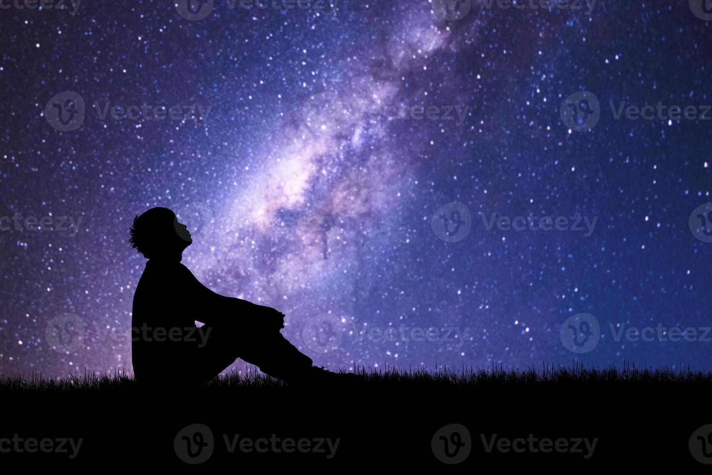 Loneliness, despair and regret concept. Lonely man in the meadow against the backdrop of stars and the Milky Way. photo