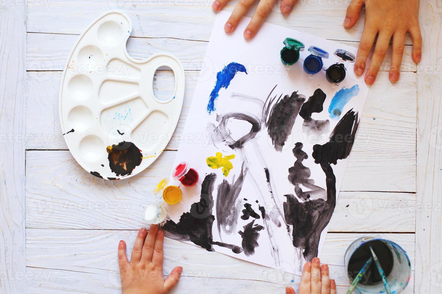 view from above. child draws a brush and paints top view. Flat lay art tools for painting.Artwork workplace photo