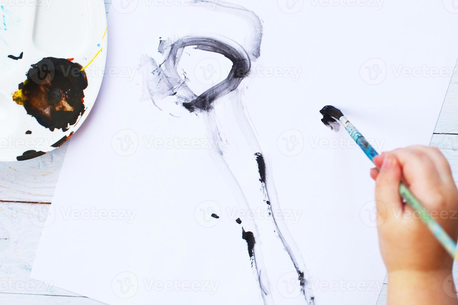 view from above. child draws a brush and paints top view. Flat lay art tools for painting.Artwork workplace photo