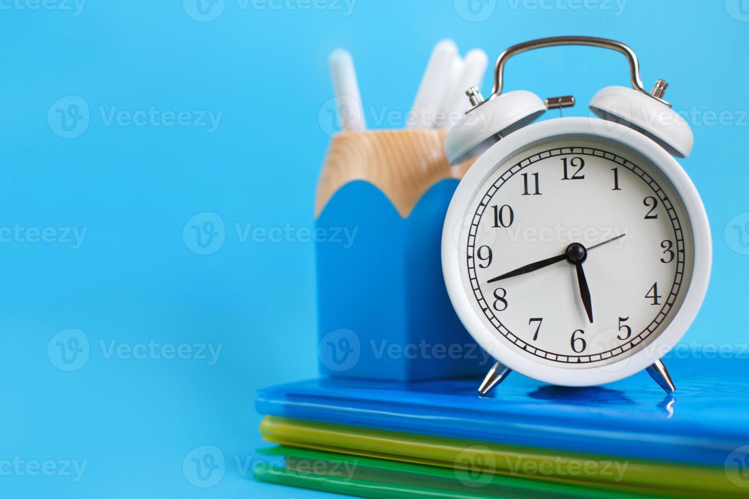 Textbooks and alarm clock on a blue background. Back to school. Concept Education or business photo