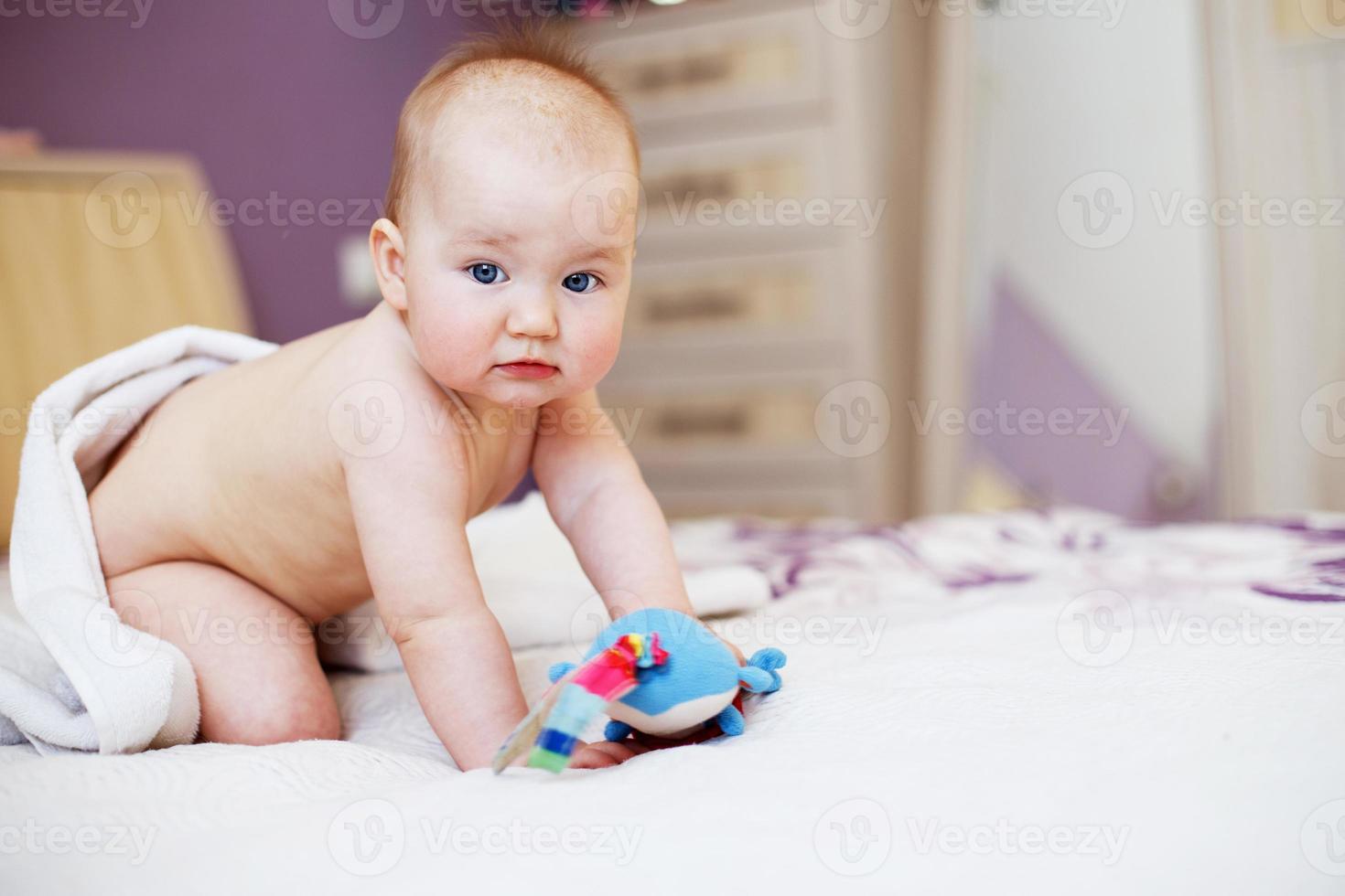 lindo bebé mirando a la cámara bajo una toalla blanca. retrato de un niño lindo foto