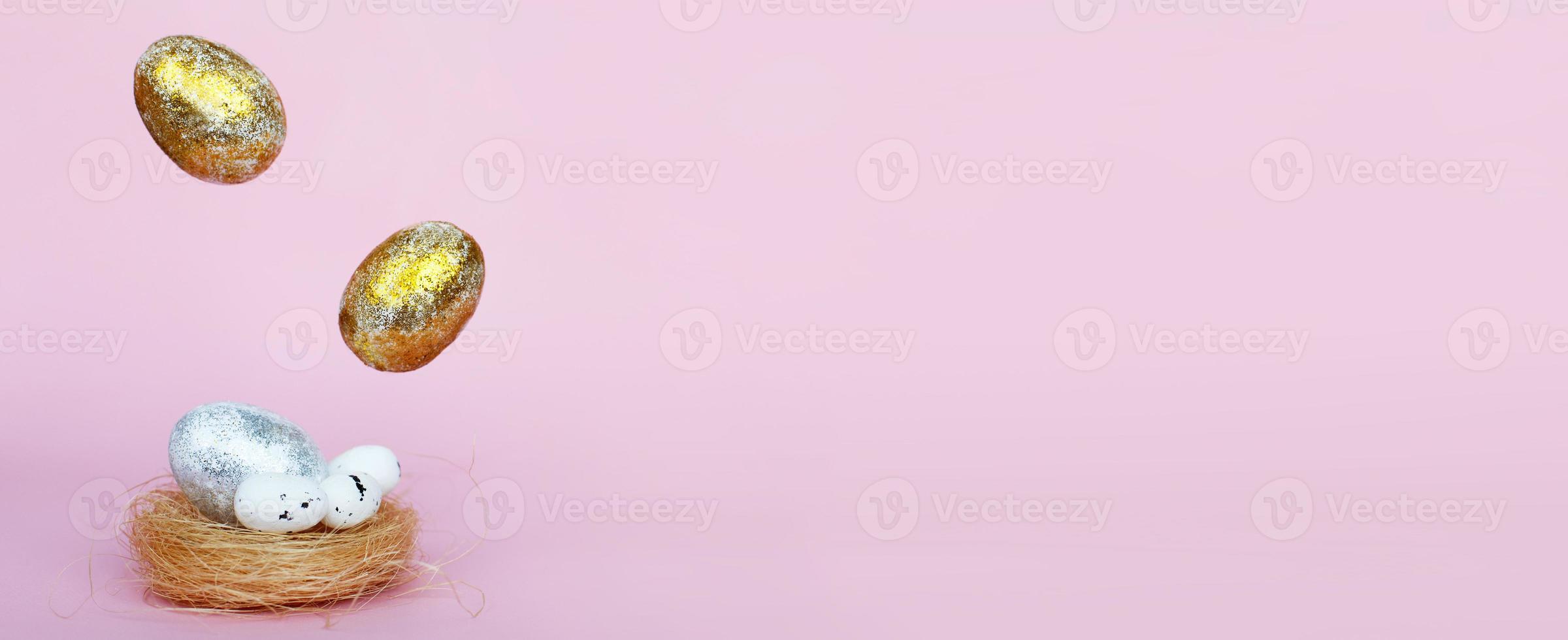 Gold and silver Easter eggs levitation to the nest on a pink background. Easter concept. Copy space photo