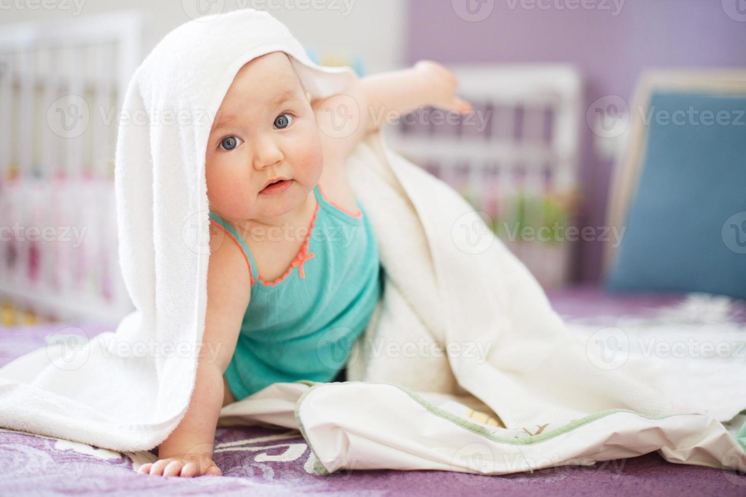 cute baby looking at camera under a white towel. portrait of a cute child photo