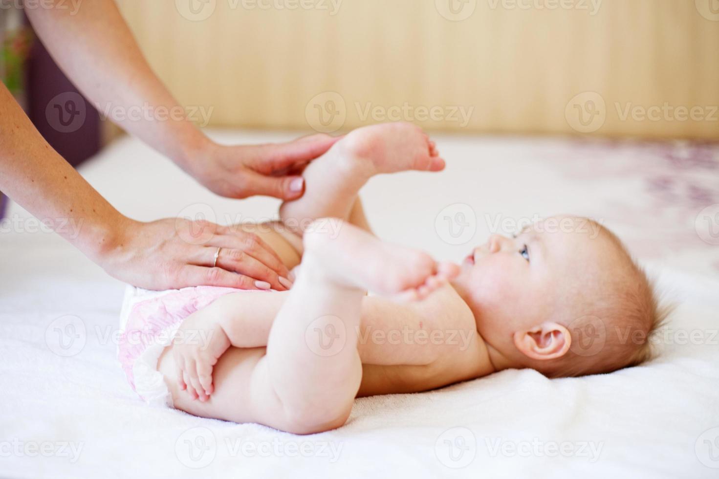 mother changing the diaper of her baby at home photo