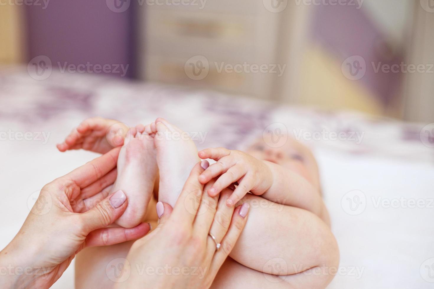 Mom does gymnastics for a child. mom massages the baby's feet. Mom's love and tenderness. photo