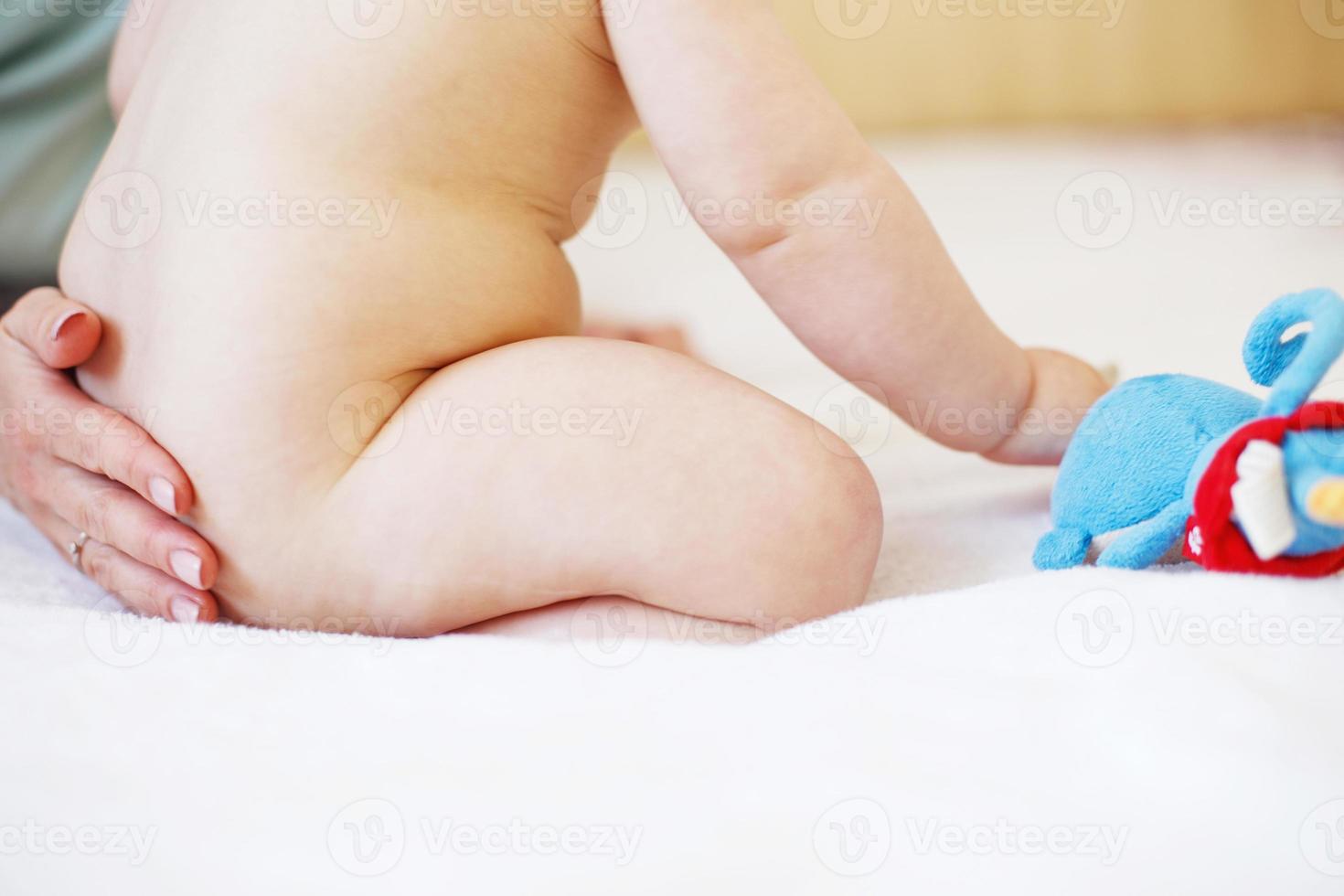 Mother and baby. Happy family. Mom's love and tenderness. Mother massaging baby in the bed at home photo