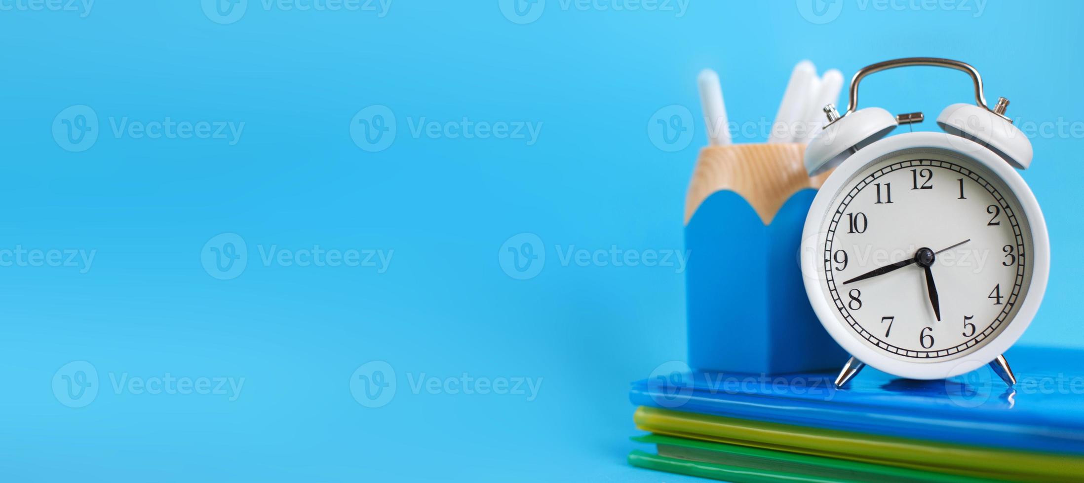 Textbooks and alarm clock on a blue background. Back to school. Concept Education or business. banner photo