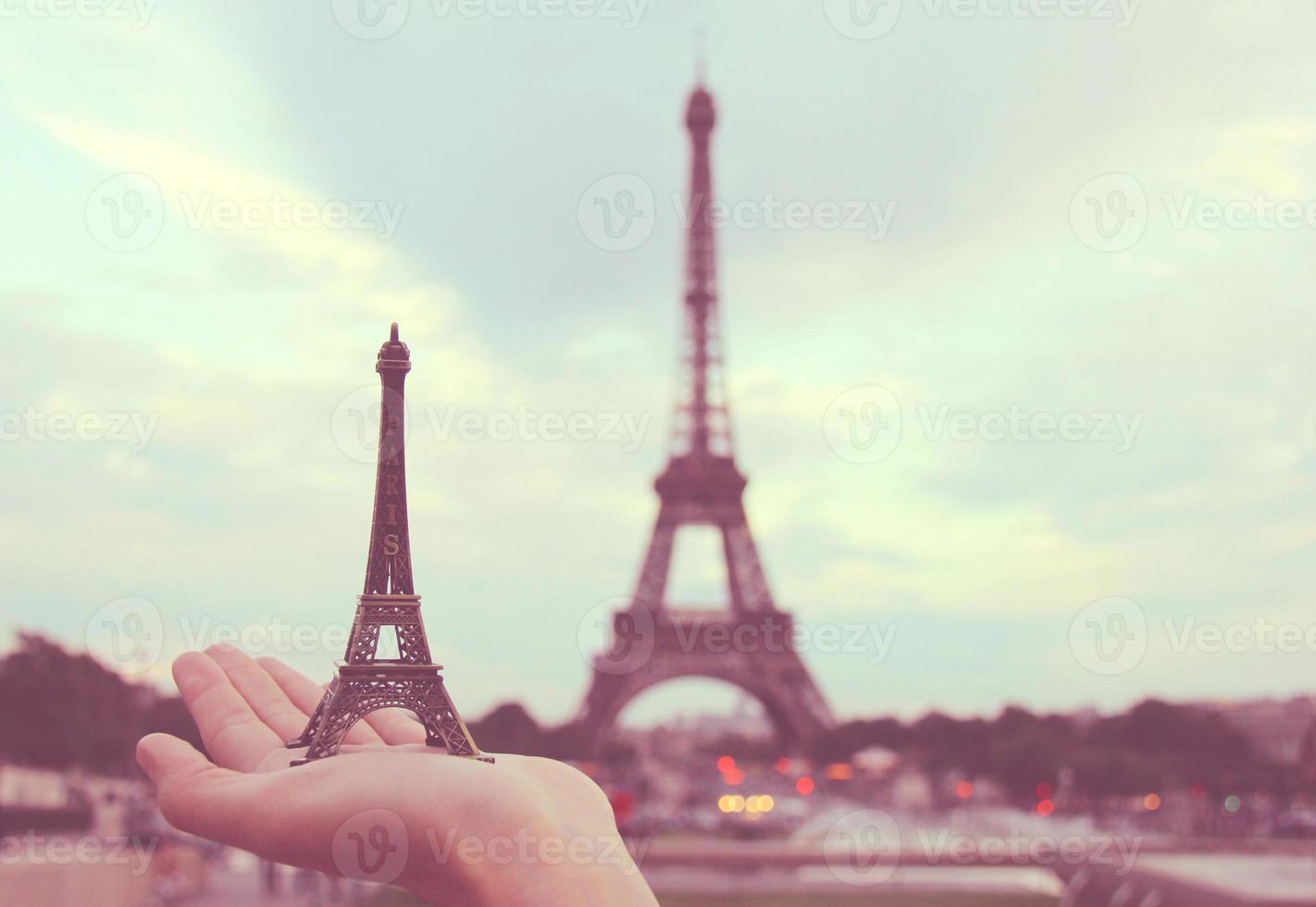 Hand holding eiffel tower model in paris, retro filter effect photo