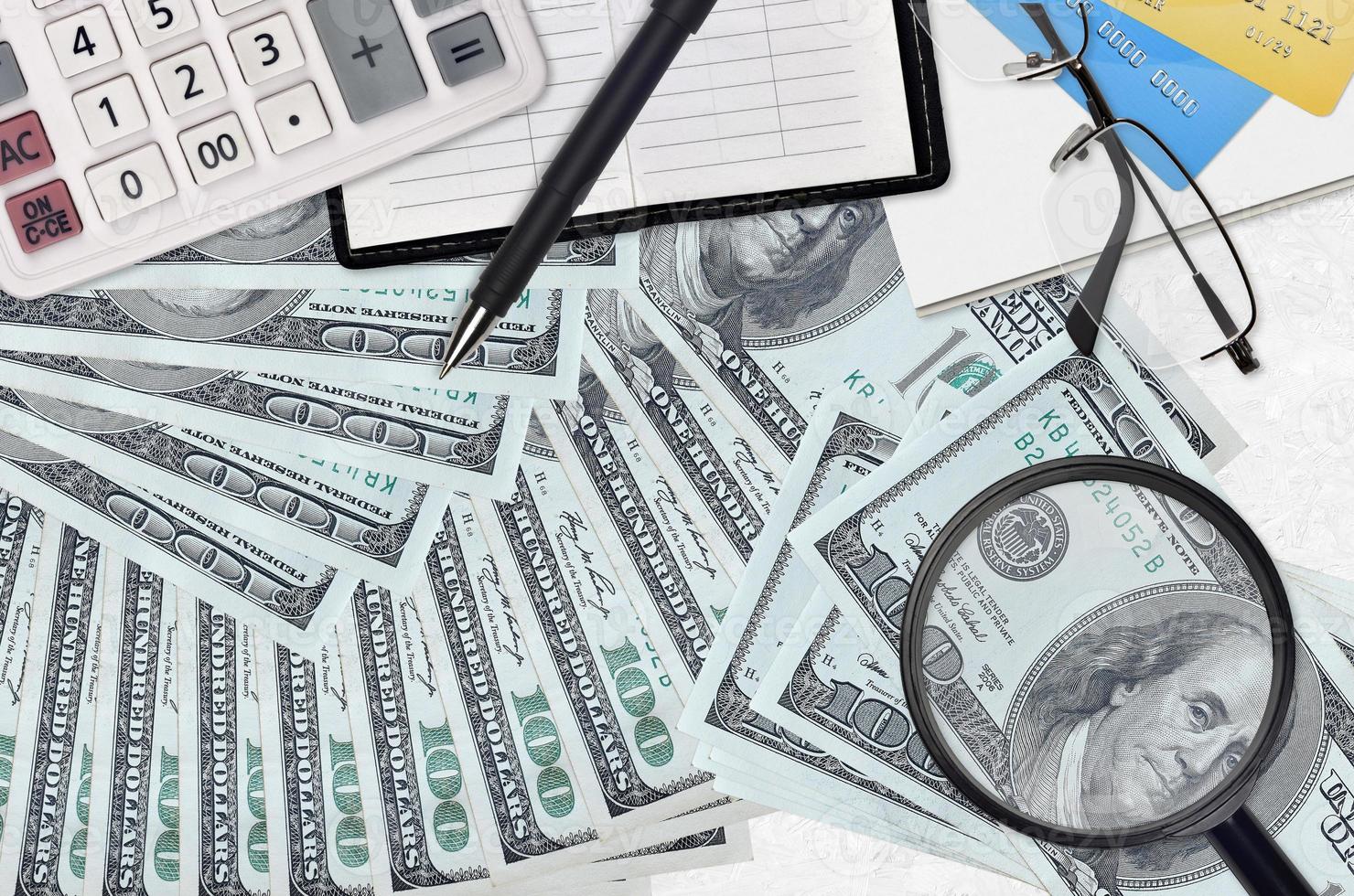 100 US dollars bills and calculator with glasses and pen. Tax payment season concept or investment solutions. Searching a job with high salary photo