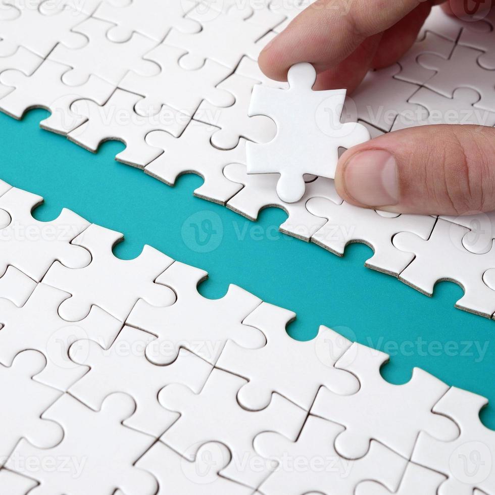 The human hand paves the way to the surface of the jigsaw puzzle, forming a blue space. The concept of overcoming the difficulties on the way to success photo