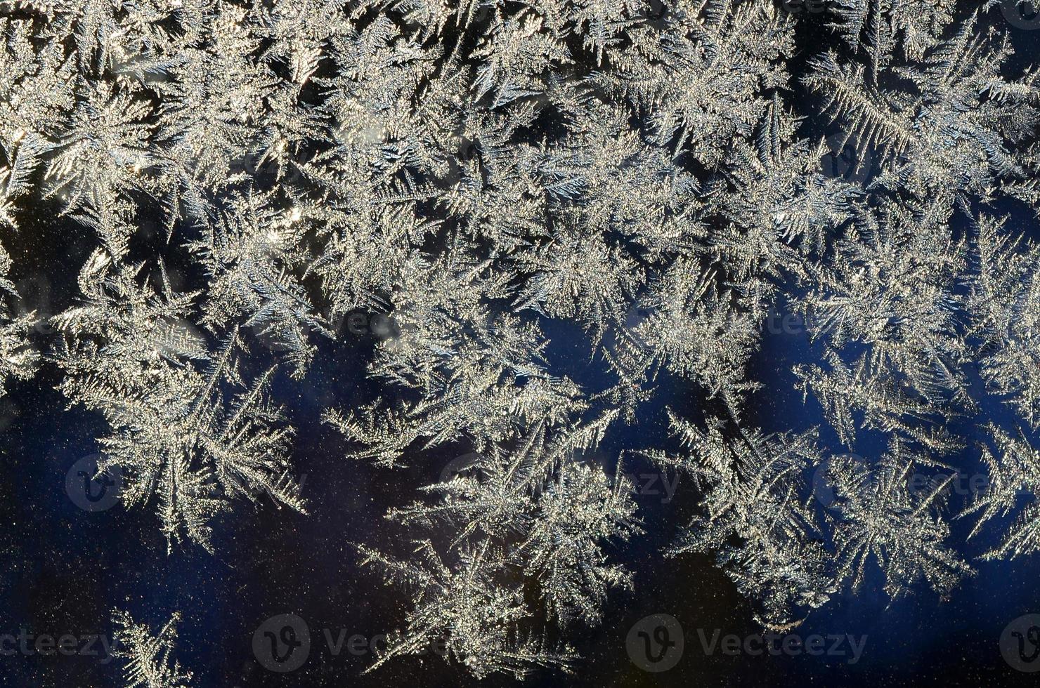 Snowflakes frost rime macro on window glass pane photo