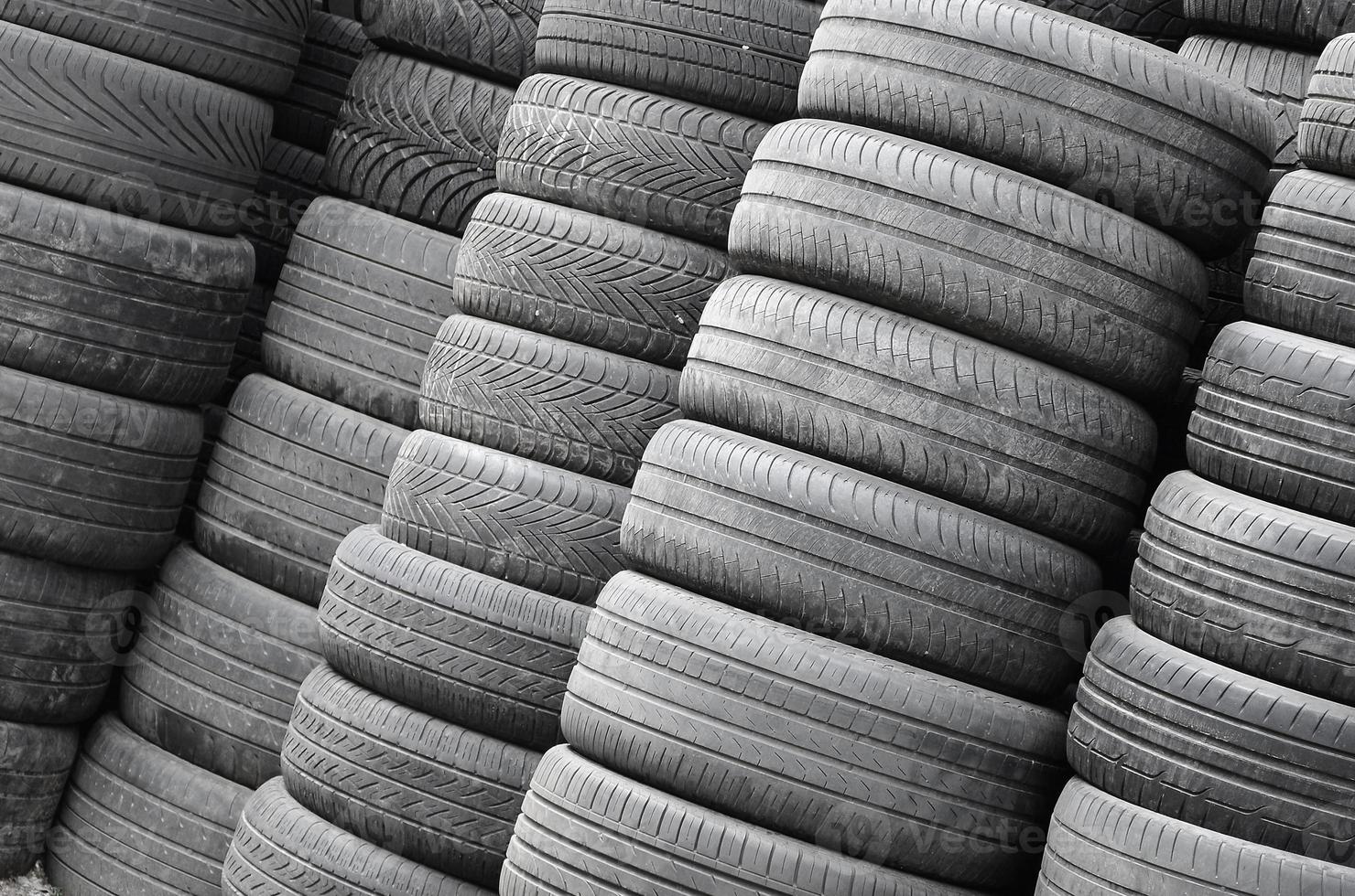 Old used tires stacked with high piles in secondary car parts shop garage photo