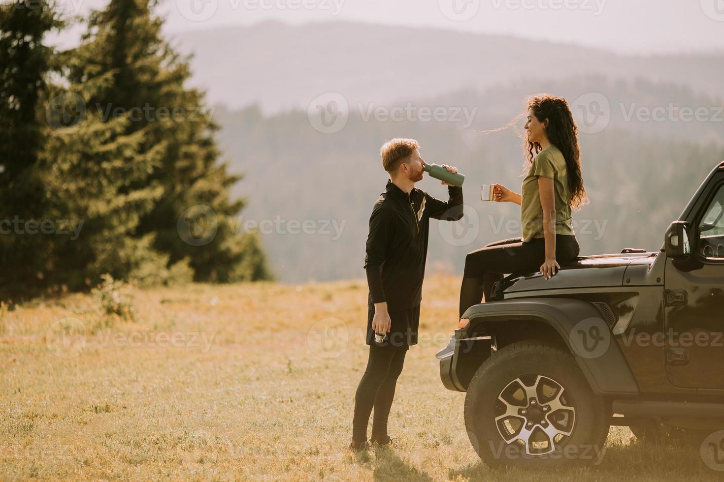 Young couple relaxing on a terrain vehicle hood at countryside photo