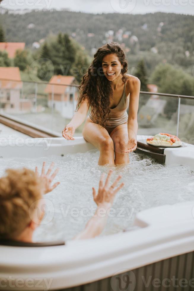Young couple enjoying in outdoor hot tub on vacation photo