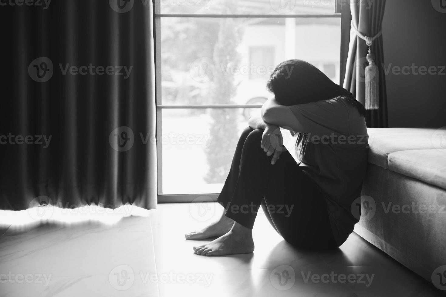 Schizophrenia with lonely and sad in mental health depression concept. Depressed woman sitting against floor at home with dark room feeling miserable. Women are depressed, fearful and unhappy. photo