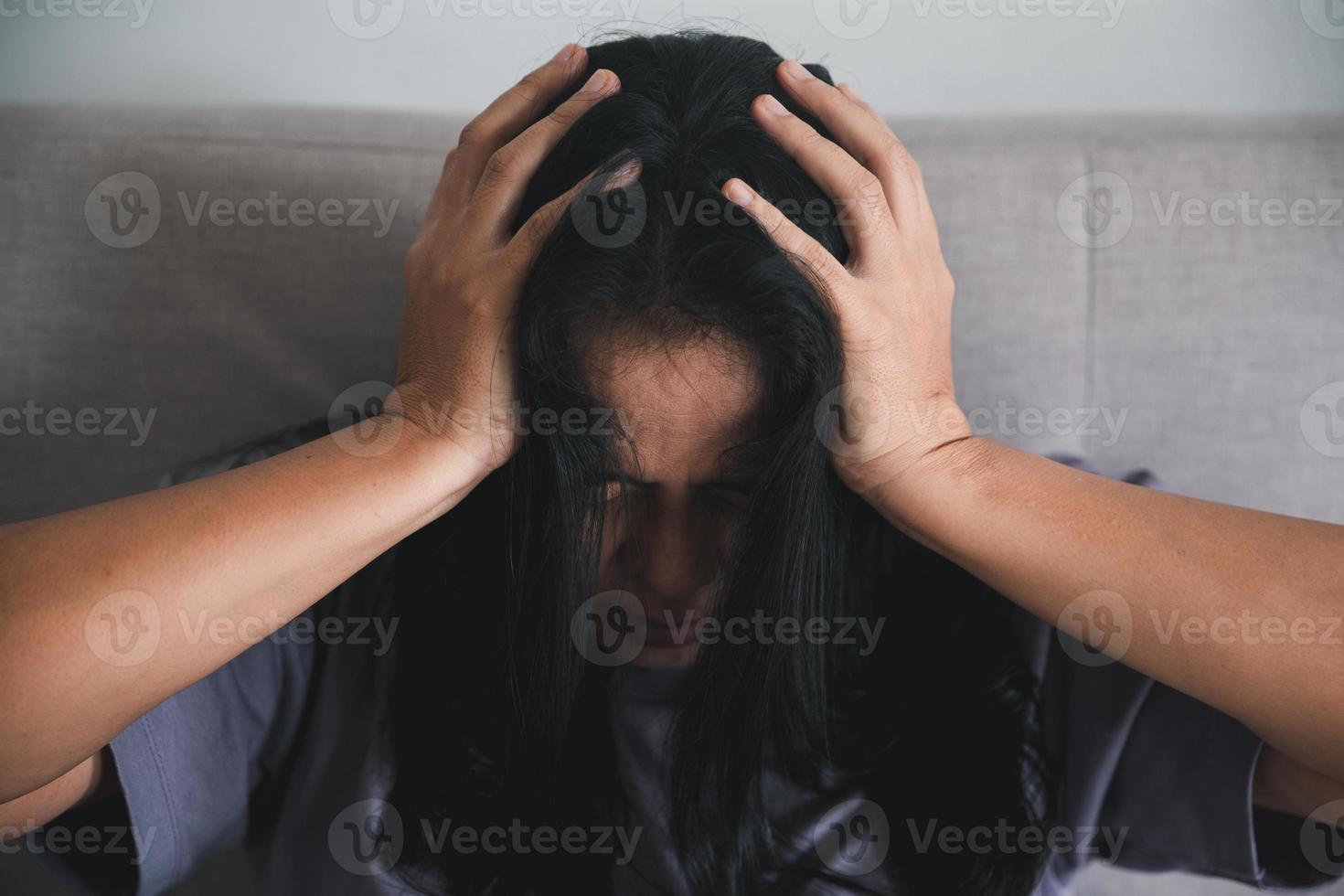 Schizophrenia with lonely and sad in mental health depression concept. Depressed woman sitting against on the sofa at home with dark room feeling miserable. Women are depressed, fearful and unhappy. photo