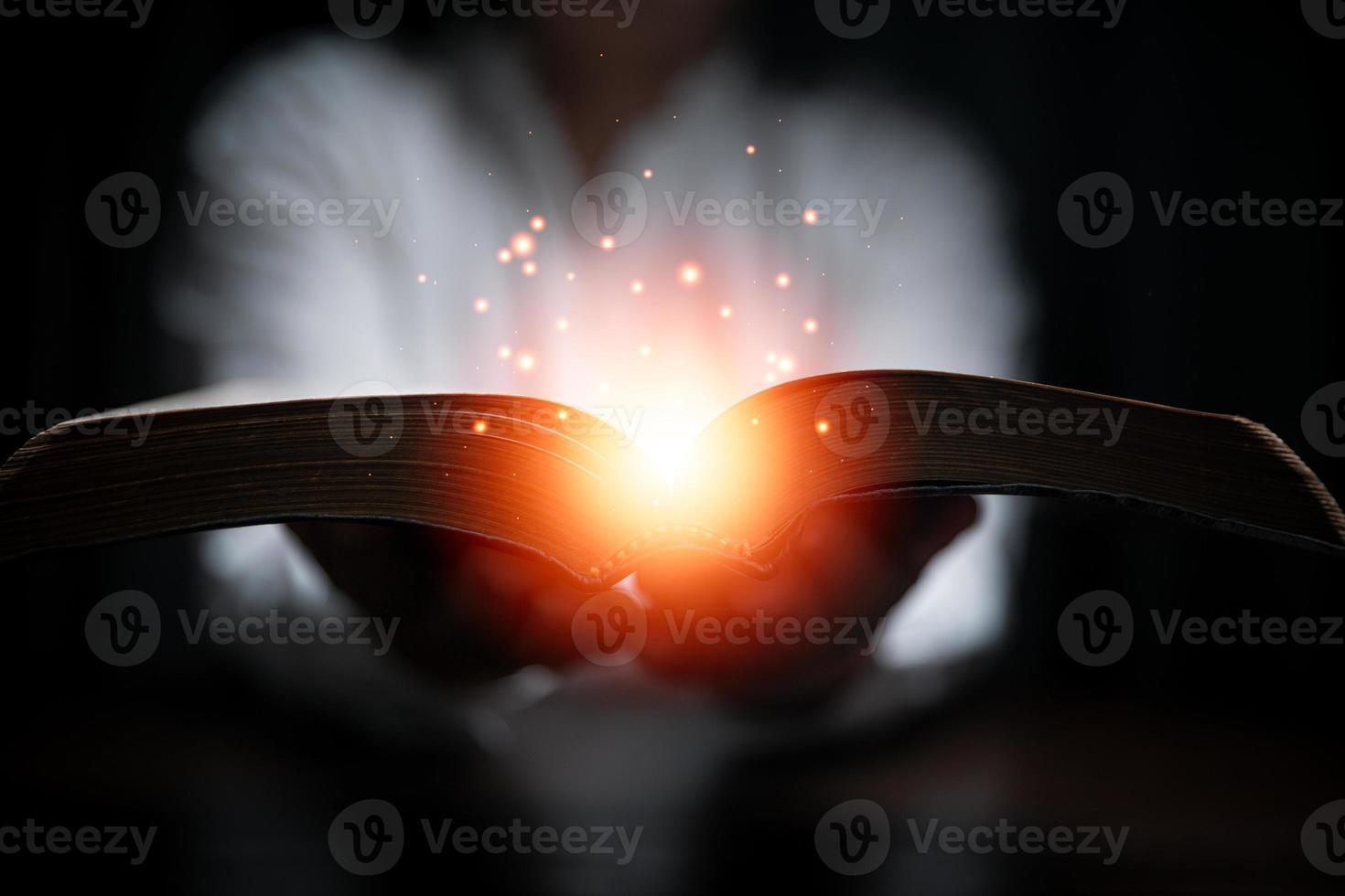 Faith with holy bible concept. Hands of a female prayer worship God with holy bible on black background in church. Christian woman who believe in Jesus read and study the grace of the holy scriptures. photo