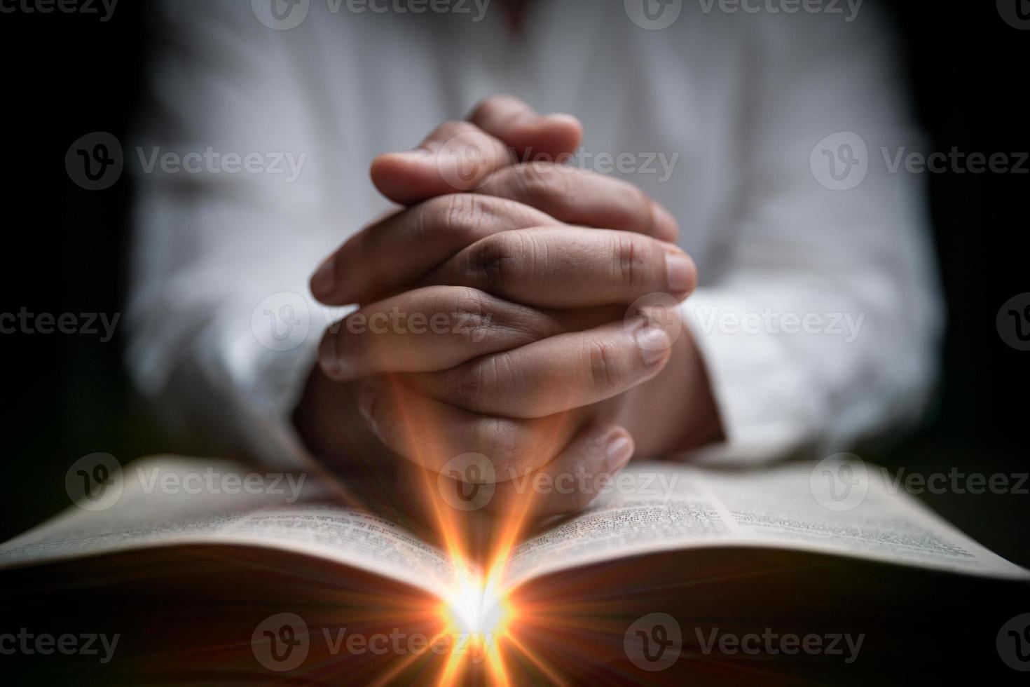 Faith with holy bible concept. Hands of a female prayer worship God with holy bible on black background in church. Christian woman who believe in Jesus read and study the grace of the holy scriptures. photo