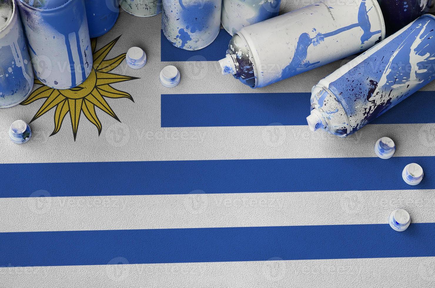 bandera de uruguay y pocas latas de aerosol usadas para pintar graffiti. concepto de cultura de arte callejero foto