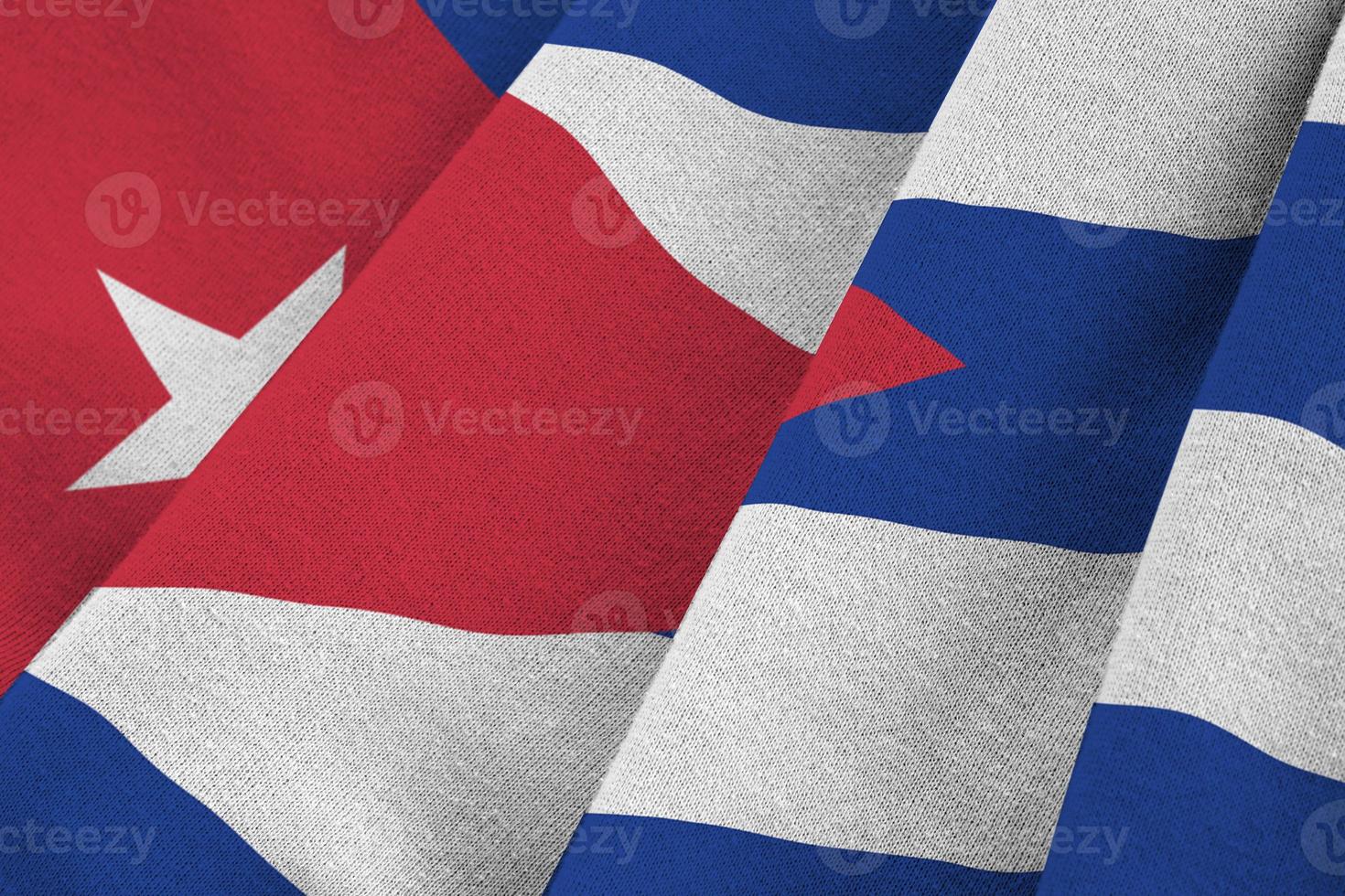 Cuba flag with big folds waving close up under the studio light indoors. The official symbols and colors in banner photo