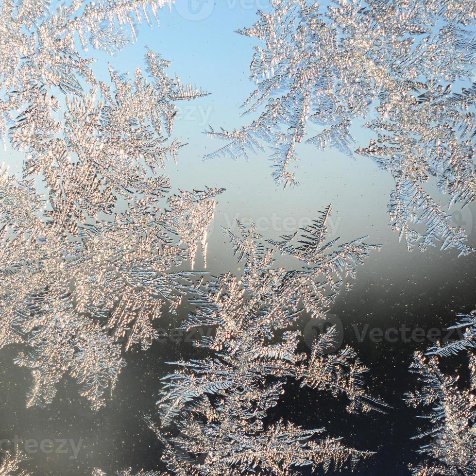 Snowflakes frost rime macro on window glass pane photo