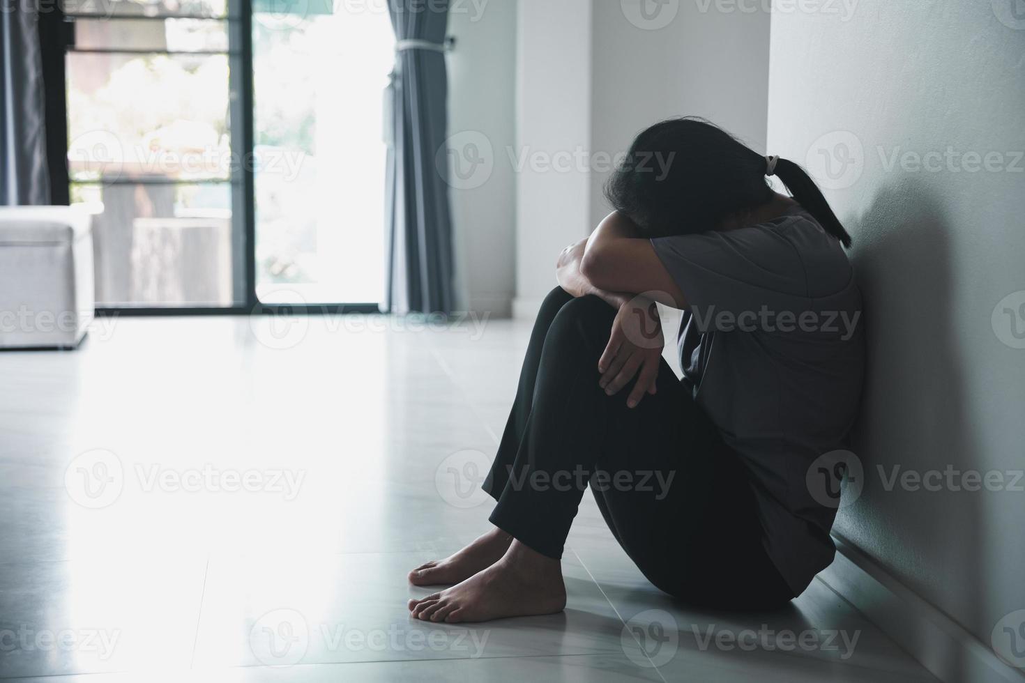 Schizophrenia with lonely and sad in mental health depression concept. Depressed woman sitting against wall at home with a shadow on wall feeling miserable. Women are depressed, fearful and unhappy. photo
