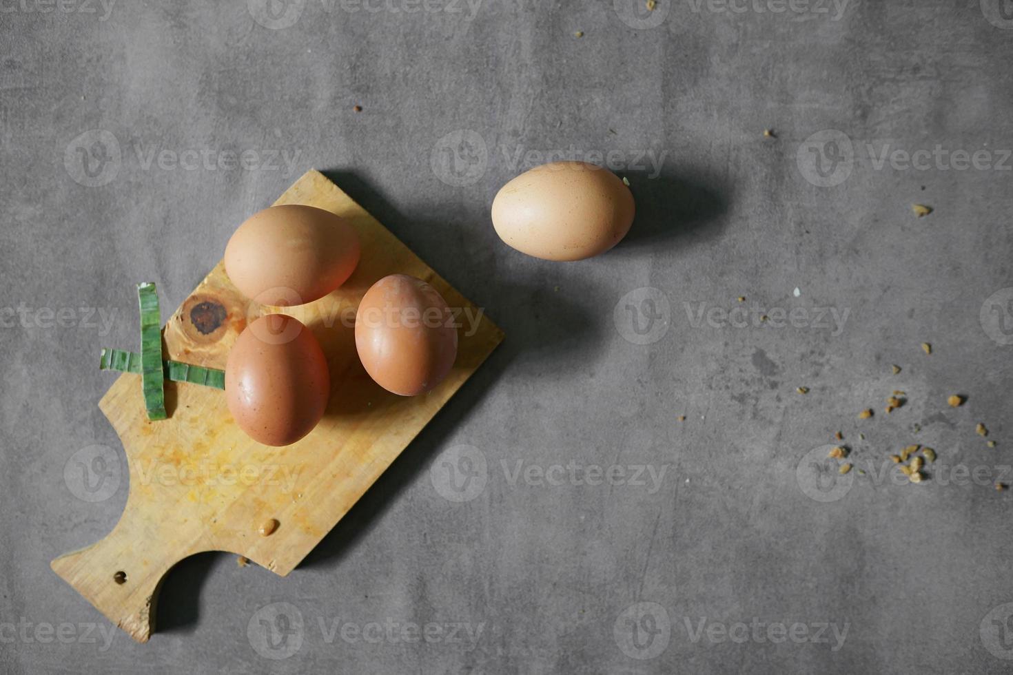 bunch of raw eggs on a cutting board with background concrete photo