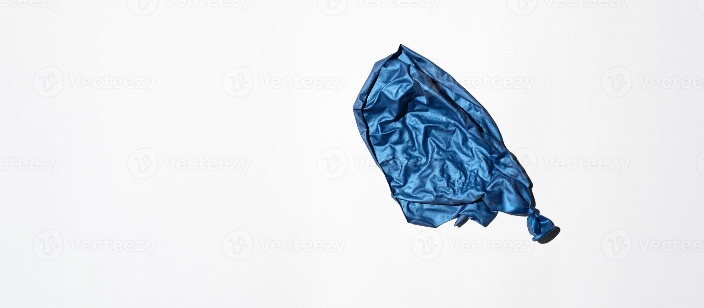 Bursting blue balloon on a white background, top view. Banner, copy space. End of holiday concept, unsuccessful party photo