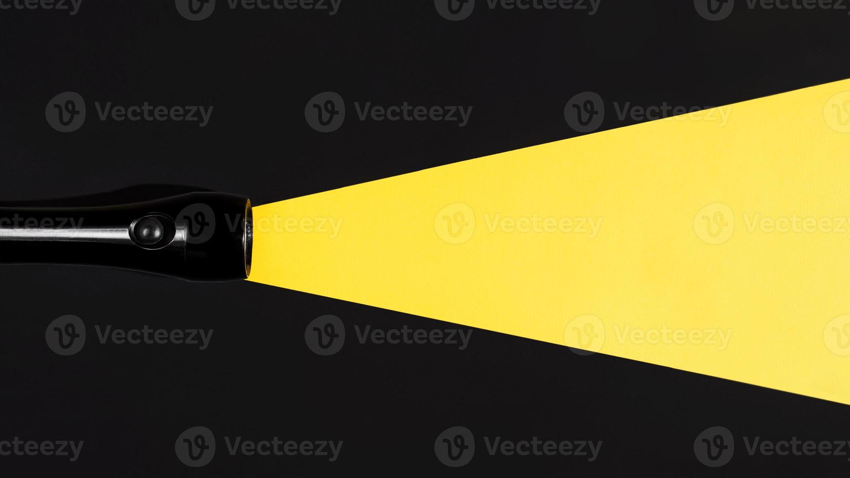 Flashlight shining on a dark background, flat lay. Light beam made of paper. Search concept, copy space. Creative photo, place for your ad. photo