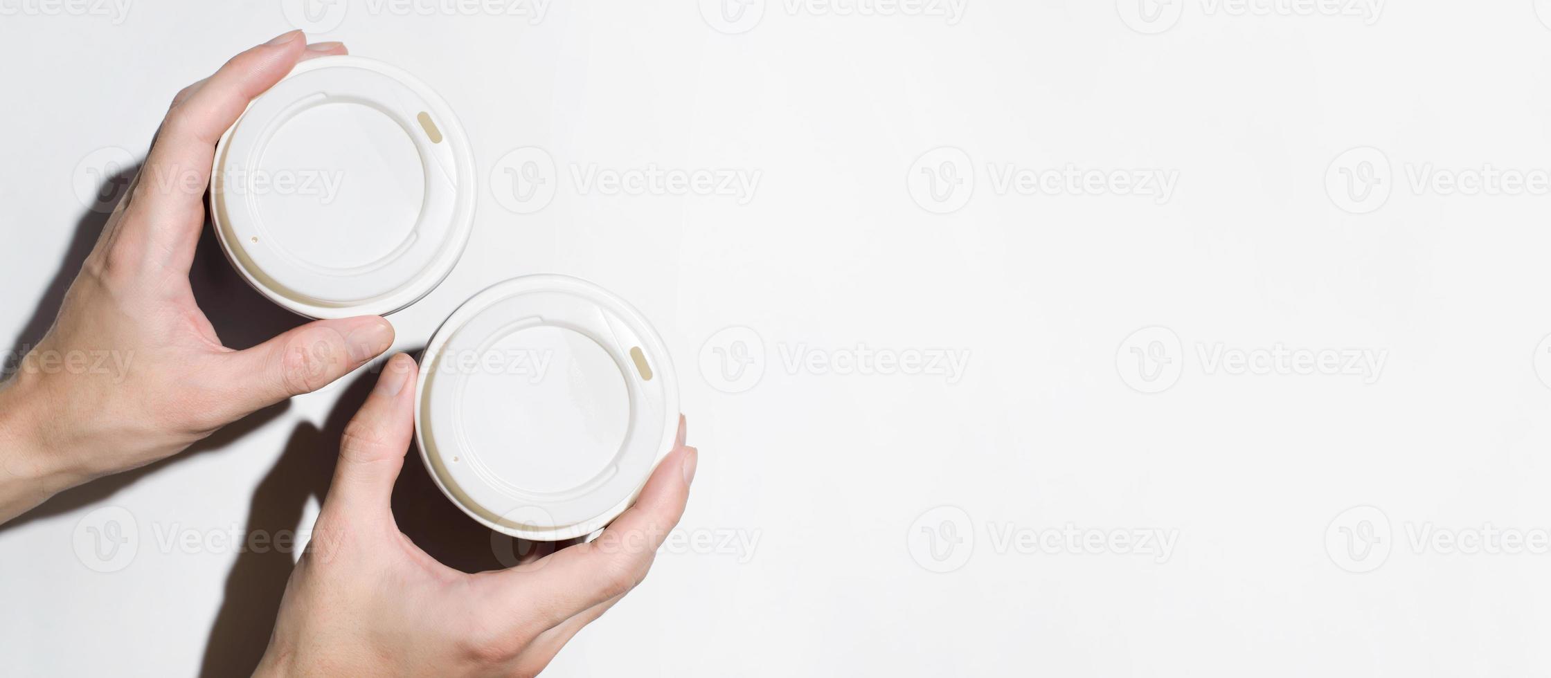 manos masculinas sosteniendo vasos desechables con café sobre un fondo blanco, vista superior. banner, espacio de copia. concepto de entrega de comida, café para llevar foto
