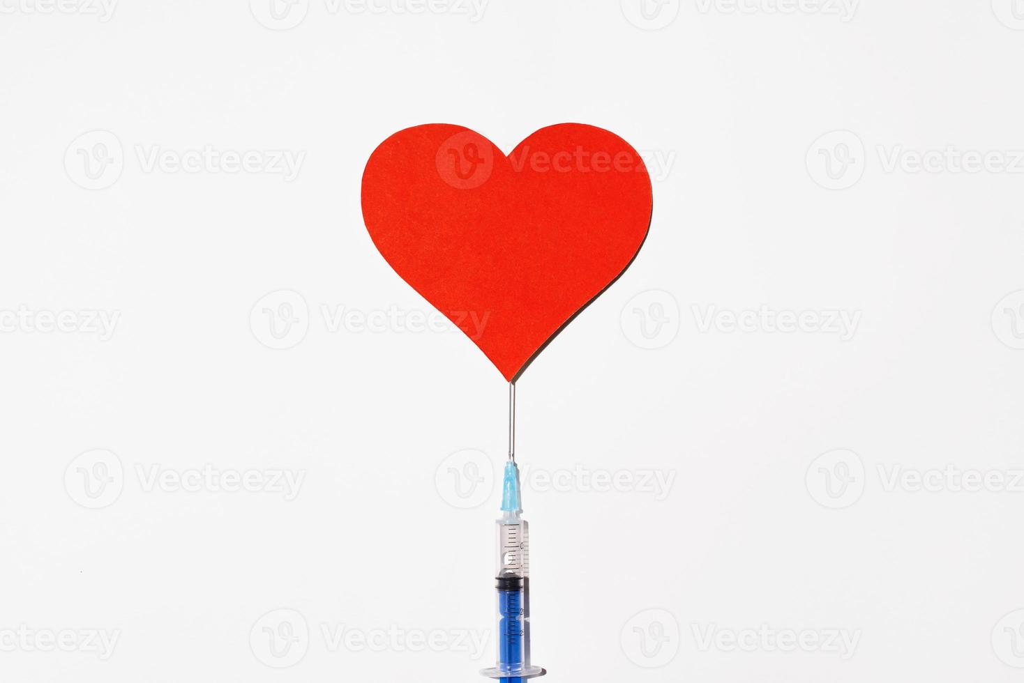 jeringa con vacuna y un gran corazón rojo sobre un fondo blanco, vista superior. concepto de vacunación segura foto