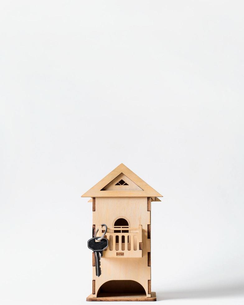 Wooden toy house with key on a light background, copy space. Concept of buying  real estate, selling house photo