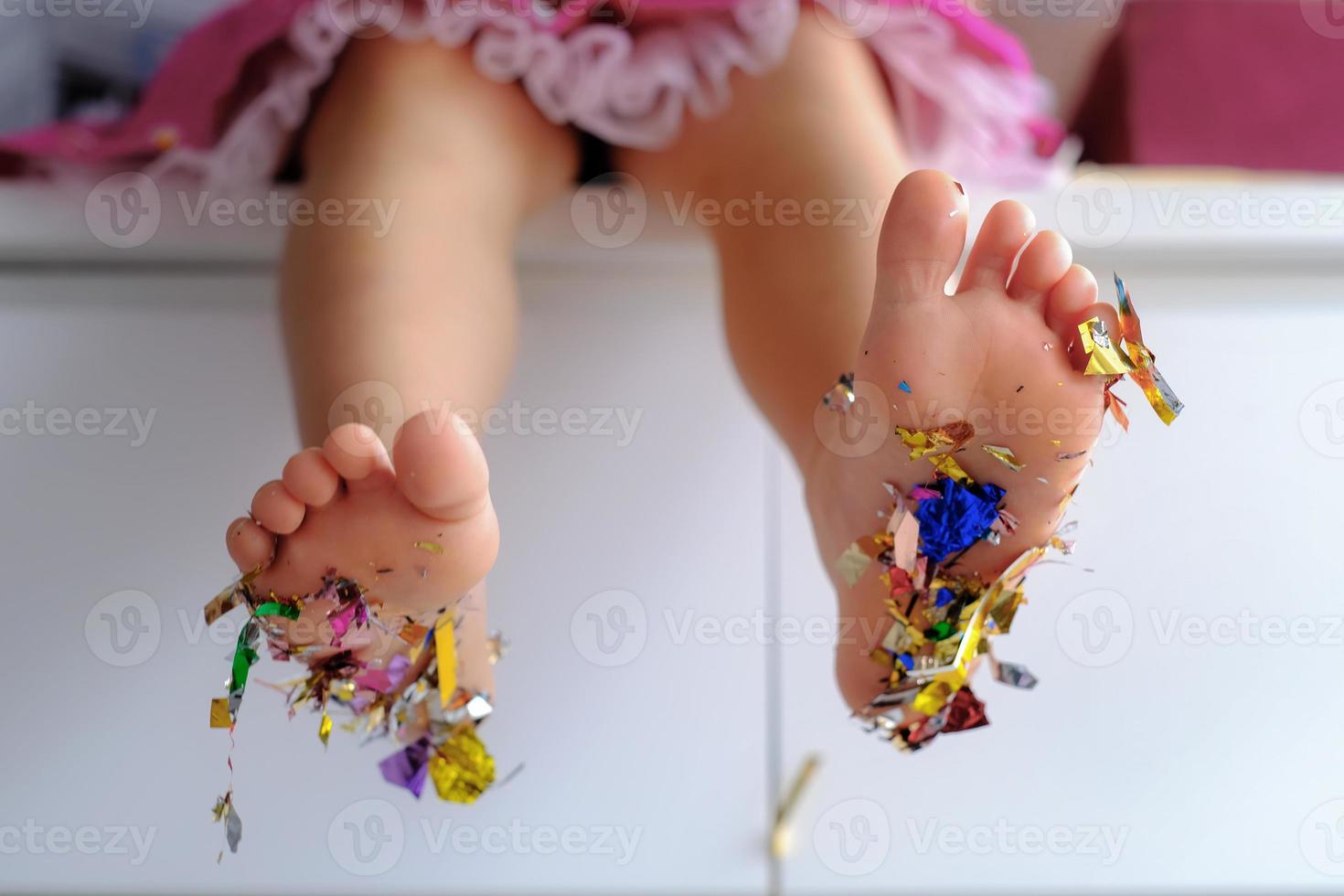 children's birthday party close up bare feet kid with colored confetti sparkles photo