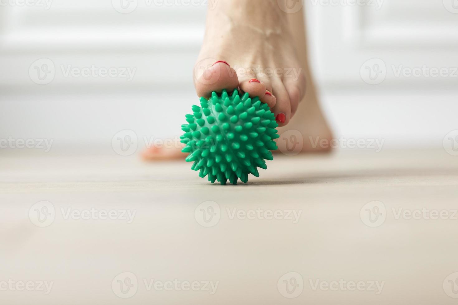 mujer haciendo ejercicio gimnástico de corrección de pie plano usando pelota de masaje en casa tema de relajación miofascial de prevenir la fatiga del pie después de usar zapatos de tacón alto pelota antiestrés foto